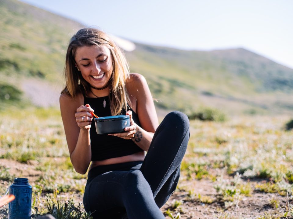 woman in black tank top and black pants sitting on ground holding blue ceramic mug during